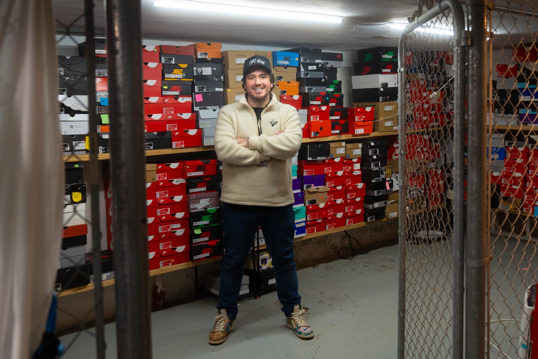 OPC Kicks owner Peter Mullin standing in front of stacks of sneaker shoe boxes.