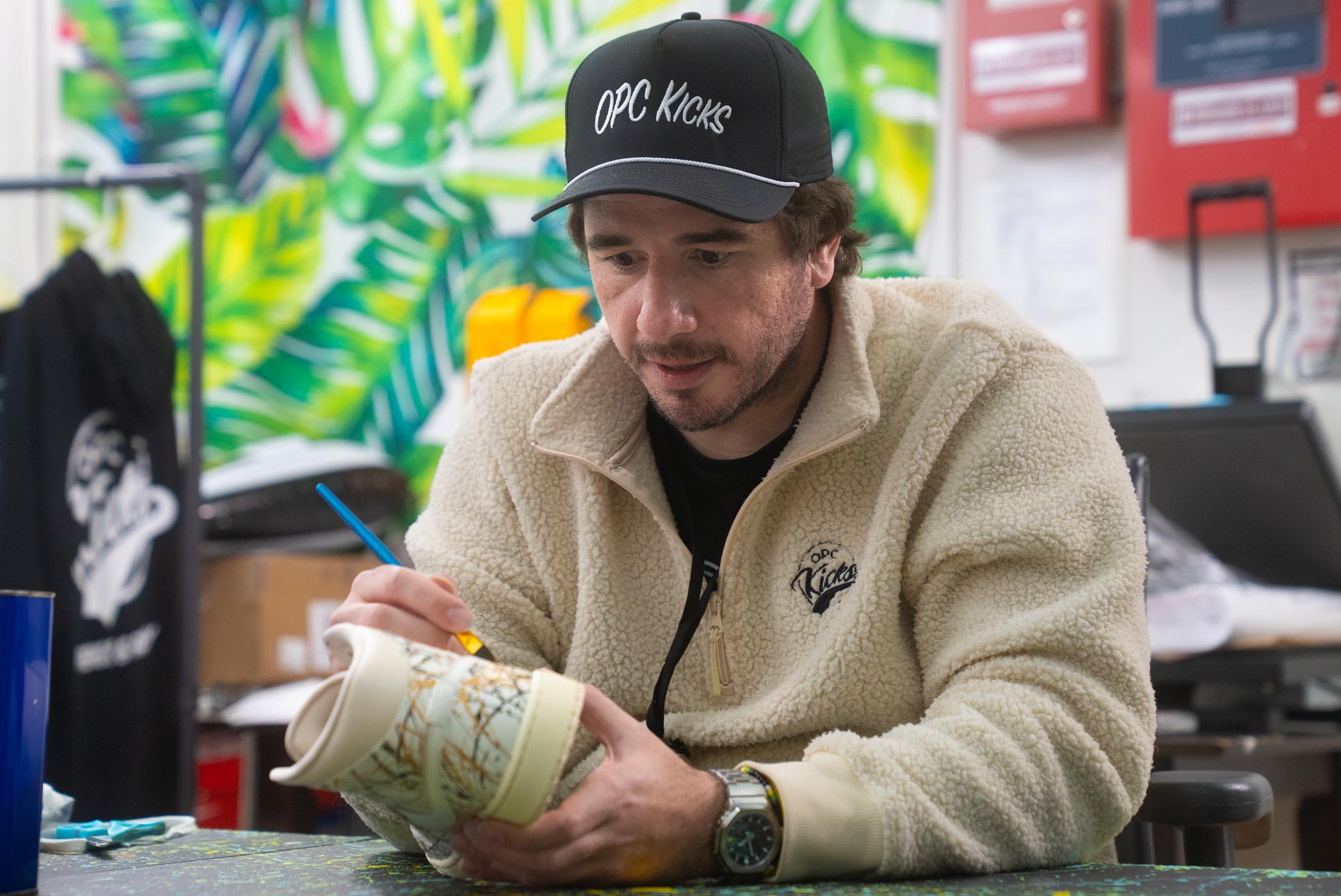 OPC Kicks owner Peter Mullin is painting a sneaker.