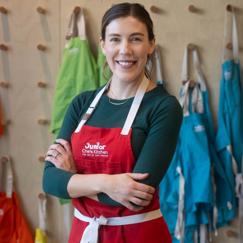 JCK founder Niki Cordell standing in front of the junior chefs' aprons.
